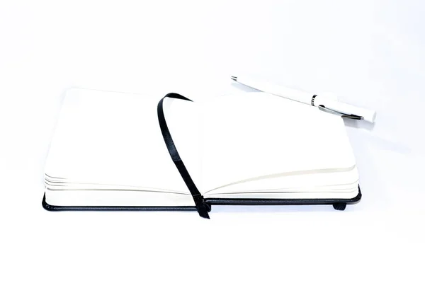 黒い開いた小さなノートパッド ペンの横に空白のライトページを持つ大規模なノートブックを展開します 白地だ 事務所 — ストック写真