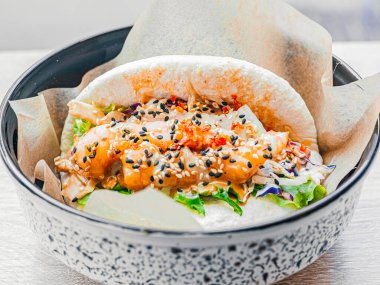 Tabağında karides olan bao. Sebzeli pirinç çörekleri, sosla doldurulmuş deniz ürünleri, susam tohumları serpiştirilmiş. Kafede, restoranda fast food. Lezzetli.