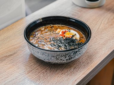 Masada siyah ve beyaz tabakta susam tohumlu kesilmiş yumurtalı sıcak miso çorbası. Üst Manzara. Japon mutfağı, kafe..