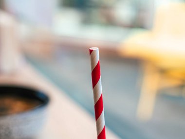 Beyaz-kırmızı spiral desenli plastik tüp milkshakeler, kokteyller, meyve suları bir dikey durur. Bokeh arkaplanı, arkaplan