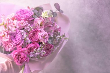 Açık pembe, mor, beyaz, narin, farklı boyutlarda küçük güller, yeşil yapraklardan çiçekler. Kağıt ambalaj. Metin için yer