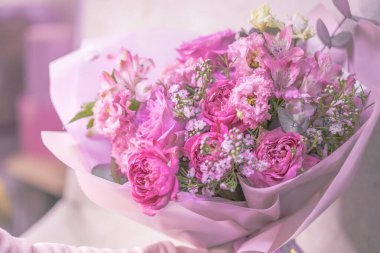 Açık pembe, mor, beyaz, narin, farklı boyutlarda küçük güller, yeşil yapraklardan çiçekler. Kağıt ambalajlama. 