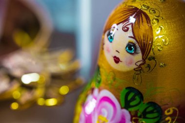 Matryoshka 'nın güzel yüzü, geleneksel Rus babuşka bebeği, istifleme bebeği, altın, yeşil, sarı, pembe renkte yuvalama bebeği. Makro. Mesaj için yer. Yakın plan. Bulanık bokeh arkaplanı