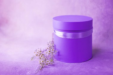 Parlak mor leylak yuvarlak çiçek hediye paketi kurdeleli, dallı iğne ve küçük çiçekler. Silindirik şekilli. Mesaj için yer. Pembe tek renkli.. 