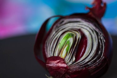 Kırmızı filizlenmiş soğanları siyah bir tabakta ikiye böl. Yan görüş. Mesajın için yer aç. Derin renklere sahip kavramsal makro fotoğrafçılık