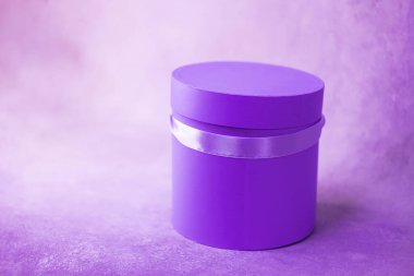 Parlak mor leylak yuvarlak çiçek hediye paketi ve kurdele. Silindirik şekilli. Mesaj için yer. Pembe arka plan. Tek Renkli