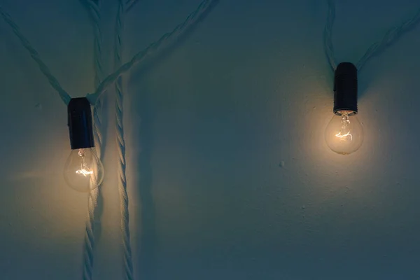 Two Small Bulbs Glowing Warm Yellow Light Hang Blue Wall — Stock Photo, Image