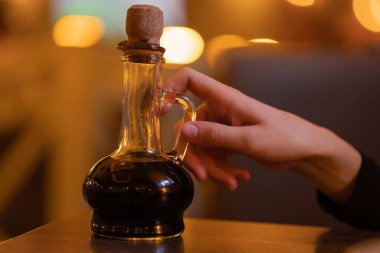 Elinde balzamik sirke, yağ, ahşap mantarlı sos, ince boynunda İtalyan mutfağı, kafe, restoran, sıcak bulanık arka plan.