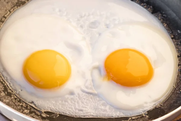 Gotowane Jajka Smażone Dwóch Jasnych Okrągłych Surowych Żółtek Czarnej Patelni — Zdjęcie stockowe
