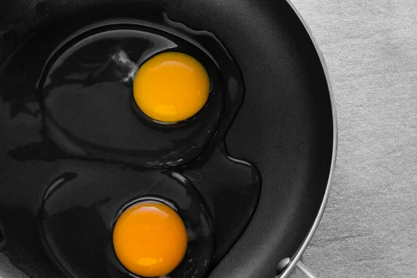 Dwa Surowe Jajka Jasnożółtymi Żółtkami Przezroczystymi Białkami Czarnej Patelni Błyszczące — Zdjęcie stockowe