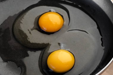 Koyu siyah bir tavada çiğ beyaz yumurta sarısı. Basit bir kahvaltı olarak yumuşak, yağda yumurta pişirmek. Yakın çekim, üst görünüm