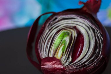 Kırmızı filizlenmiş soğanları siyah bir tabakta ikiye böl. Yan görüş. Mesajın için yer aç. Derin renklere sahip kavramsal makro fotoğrafçılık