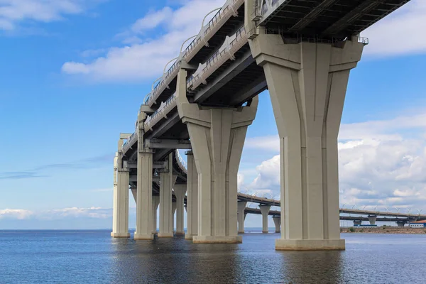 Büyük yuvarlak otoyol manzarası, kontrol erişimli otoyol köprüsü, bulutlu mavi gökyüzünün arka planına karşı. Şehrin kıyısı yakınındaki denizin üzerinden geçen yol. Saint Petersburg, Avrupa