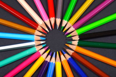 Siyah arkaplan üzerine dizilmiş renkli kalemler.