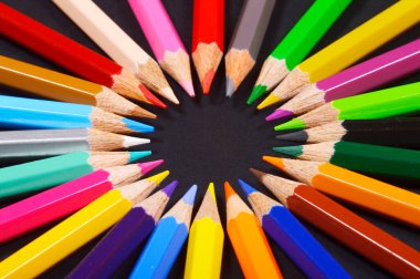 Siyah arkaplan üzerine dizilmiş renkli kalemler.