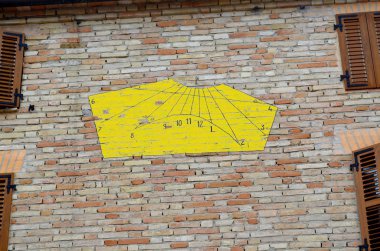 Yellow sundial on a house wall in Italy clipart