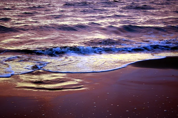 Havet vågor under en färgstark solnedgång över en vacker och romantisk strand — Stockfoto