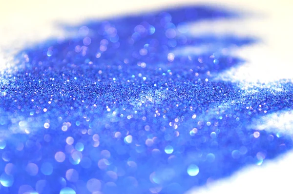 Onscherpe achtergrond van blauwe glitter schittert op witte ondergrond — Stockfoto