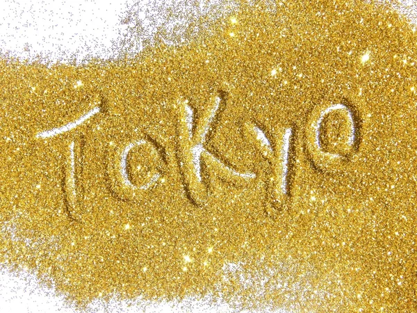 Blurry inscription Tokyo on golden glitter sparkles on white background