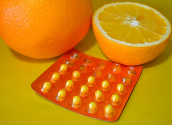 Naranjas y vitamina C sobre fondo amarillo — Foto de Stock