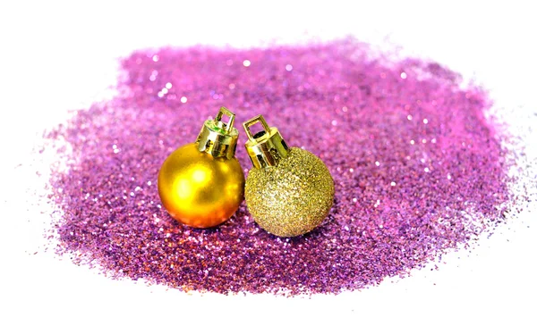 Deux boules de Noël dorées sur paillettes violettes sur fond blanc — Photo