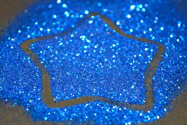 Blurry abstract background with star of blue glitter sparkles on black surface — Stock Photo, Image