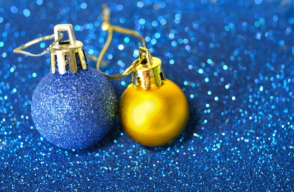 Blue and golden Christmas balls on blurry background of blue glitter — Stock Photo, Image
