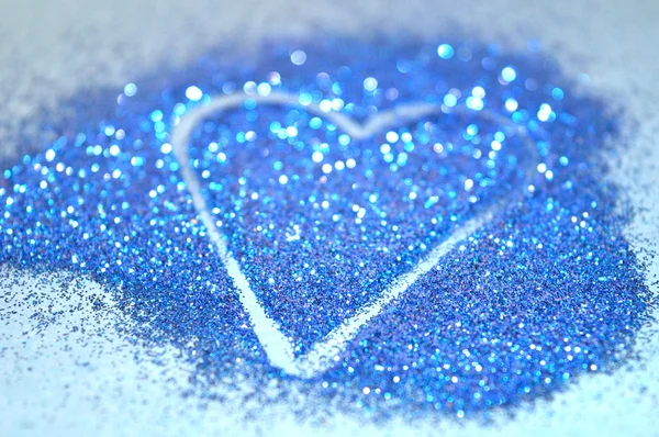 Verschwommener abstrakter Hintergrund mit Herz aus blauem Glitzern auf blauer Oberfläche — Stockfoto