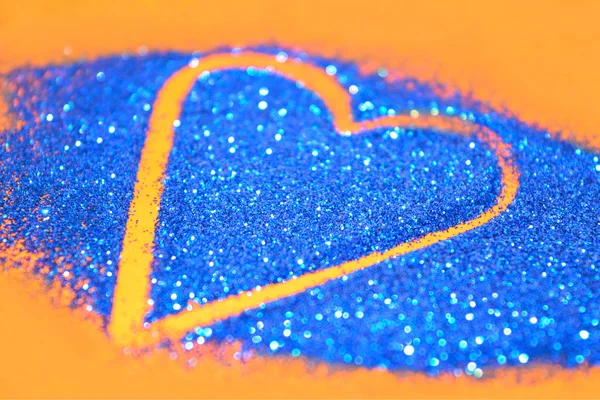 Suddiga abstrakt bakgrund med hjärta av blå glitter glitter på orange yta — Stockfoto