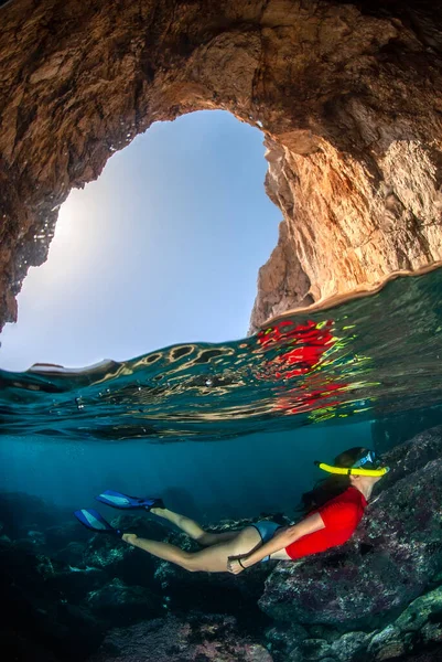 Büyük bir mağaranın içinde kristal berrak sulara dalan bir kızın görüntüsü.