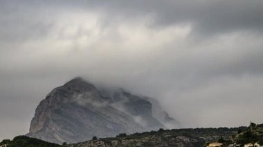 İspanya 'nın Alicante kıyısındaki Montgo dağının etrafında hareket eden gri bulutlar