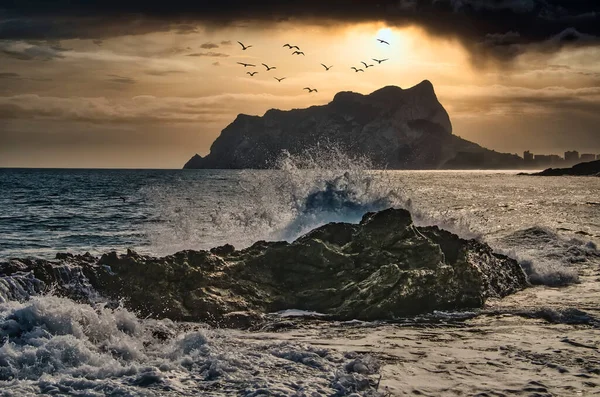 岩の中に飛び散る波の日没時の劇的な風景 — ストック写真