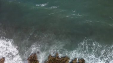 Kameranın hareketi dalgalı ve kayalık bir kıyı manzarasını gösteriyor.