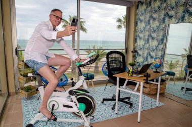 Evdeki çok işlevli bir odada iş adamı. Aynı yerde çalışmak ve spor yapmak..