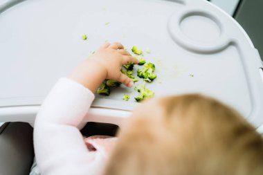 Bebek bakıcılığının erken safhalarında elleriyle brokoli yiyor.