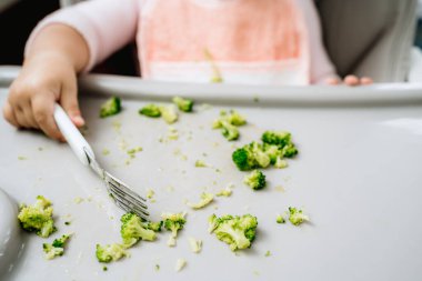 Küçük beyaz kız mutfaktaki bir besleyiciden çatalla sebze topluyor, vejetaryen ya da vejetaryen sağlıklı çocukluk hayatı, bebek sütten kesme konseptine öncülük ediyor.