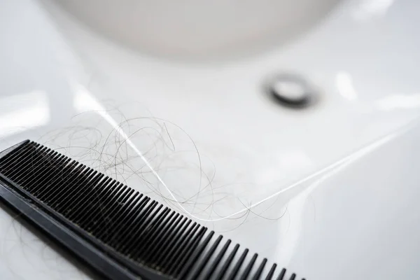 a close-up comb with hairs. Treatment for alopecia in men, hair loss. thinking about hair transplantation