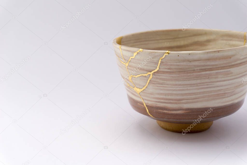 Kintsugi Japanese beige tea cup , gold cracks, antique Japanese restoration technique. Japanese tea ceremony cup restored with gold.