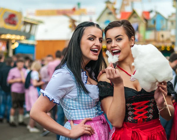 Twee jonge vrouwen in Dirndl jurk of klederdracht, lachen met cotton candy floss op het Oktoberfest Rechtenvrije Stockfoto's