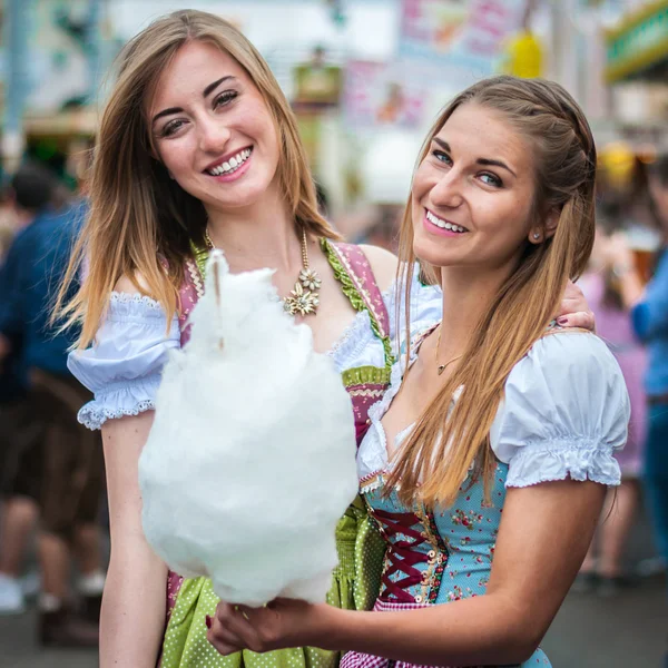 Twee jonge vrouwen in Dirndl jurk of klederdracht, glimlachend met cotton candy floss op het Oktoberfest Stockfoto