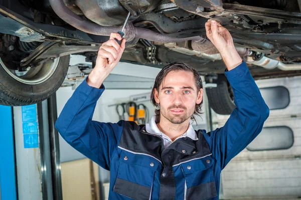 Mechanic checking the condition of a lifted car — Stock Photo, Image