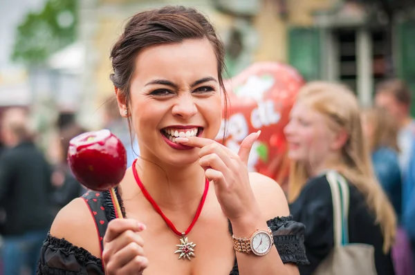 Aantrekkelijke vrouw met een rode gekarameliseerde appel op het Oktoberfest Stockfoto