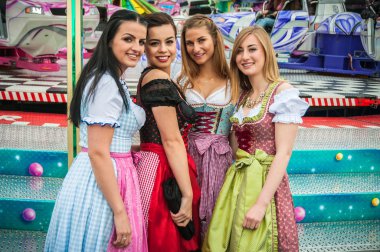 Geleneksel dirndl elbiseler ve arka planda joyride Almanca Oktoberfest, çekici ve eğlenceli woamn.