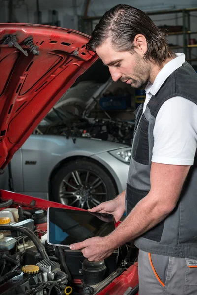 Mechanic using a tablet pc at the repair garage — Stock Photo, Image