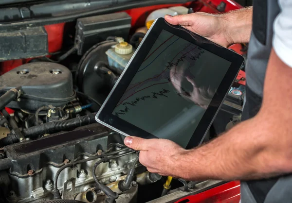 Mechanic een tablet pc gebruikt in de garage voor reparatie Rechtenvrije Stockafbeeldingen