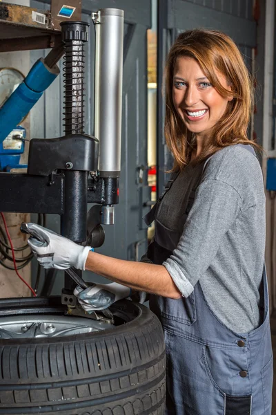 Female mechanic changing car tire. — Stock Photo, Image
