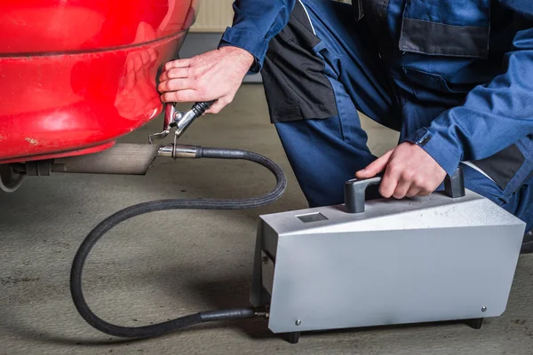 Een diagnostische sensor wordt toegepast op de ehaust van een auto door een monteur, de samenstelling en de stoffen in de uitlaatgassen te meten Stockafbeelding
