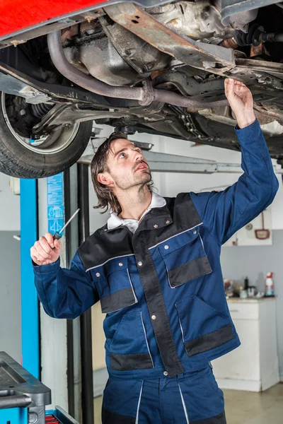 Mechanic checking the condition of a lifted car — Stock Photo, Image