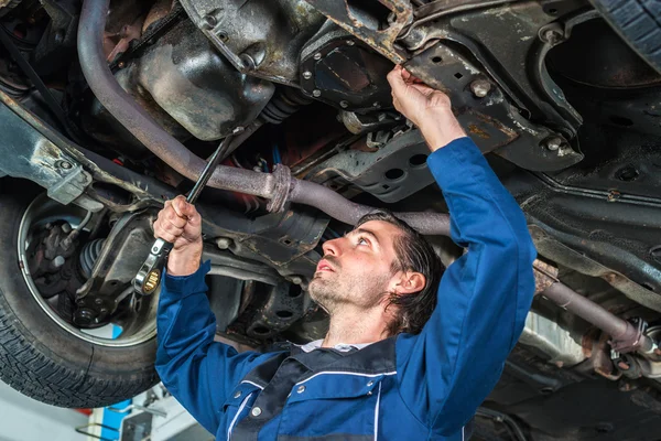 Mechanic checking the condition of a lifted car — Stock Photo, Image