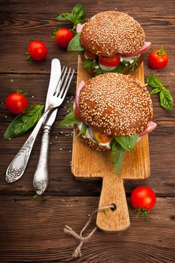 Burger pastırma, roka ve domates ahşap rustik arka plan üzerinde